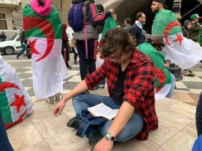 Man seated and reading during Algerian protest
