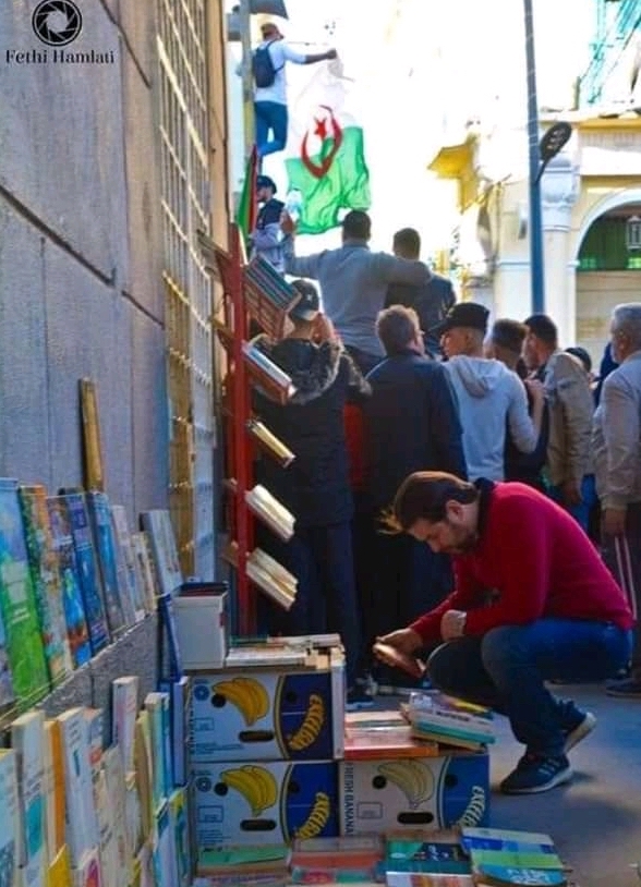 Image of man looking at books during Algerian protest