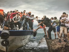People reaching from boat and from land to help each other