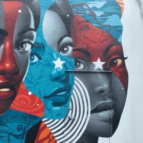 Graffiti art of three women, in a Marvel-like style with red, white, and blue.