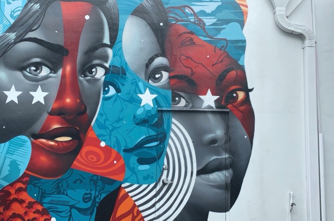 Graffiti art of three women, in a Marvel-like style with red, white, and blue.